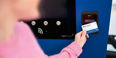 Vrouw met roze trui scant Q8 electric kaart aan Laadpunt