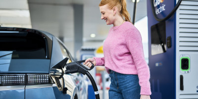 vrouw steekt lader in haar elecktrsche wagen bij Q8 electric